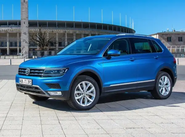 Niebieski VW Tiguan Allspace parkuje przed stadionem.