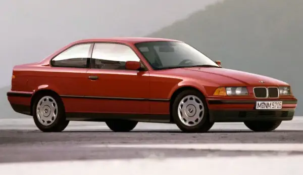 Czerwone BMW E36 coupe z lat 90. na tle szarego nieba. Klasyka motoryzacji.