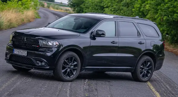Czarny Dodge Durango 3.6 na krętej drodze, otoczony zielenią.