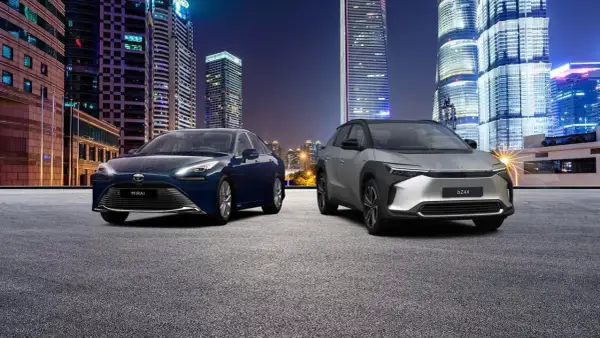 Dwa samochody, Toyota Mirai i bZ4X, na tle nocnego miasta. Zastanawiasz się, ile kosztuje samochód elektryczny?