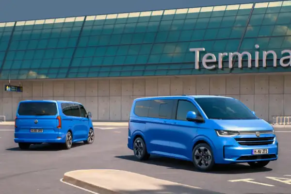 Dwa niebieskie Volkswageny Caravelle stoją przed budynkiem terminala lotniska.